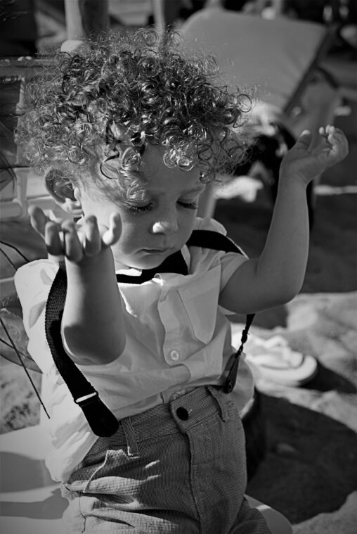 Young boy at a wedding showing his interest levels. Taking his arms out of this trouser braces.