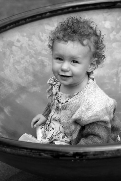 Toddler on a round-a-bout smiling. Black and white image.